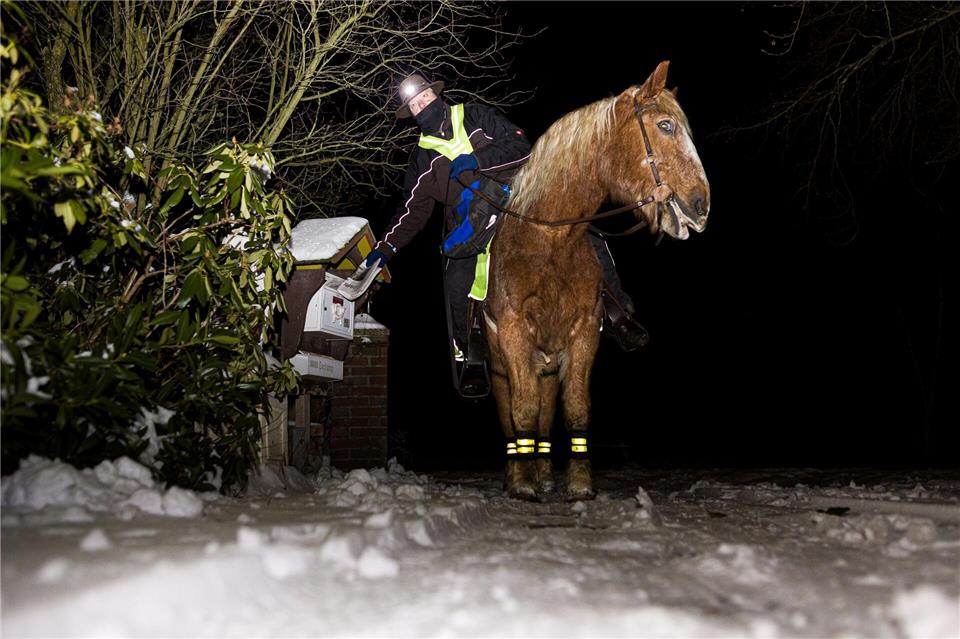 Marcus Zotan trägt am frühen Morgen auf dem Rücken seines Pferdes Wilko die Cellesche Zeitung in dem Dorf Wiedenrode im Landkreis Celle aus.Moritz Frankenberg/dpa