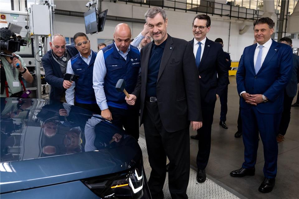 Markus Söder (CSU) bringt mit einem Hammer das BMW-Logo an einem Auto an.Sven Hoppe/dpa