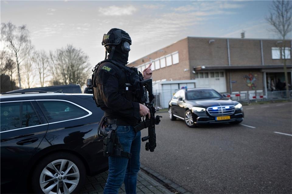 Maskierte und bewaffnete niederländische Polizisten bewachen einen Transport mit einigen der Verdächtigen, die vor dem Hochsicherheitsgebäude des Gerichts in Amsterdam eintreffen.