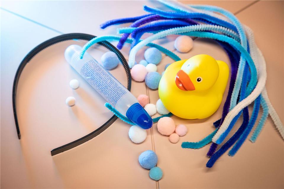Material für den Enten-Kopfschmuck: ein Quietsche-Entchen, ein Haarreif, viele Pfeifenreiniger und Bommeln sowie Kleber.Christin Klose/dpa-tmn