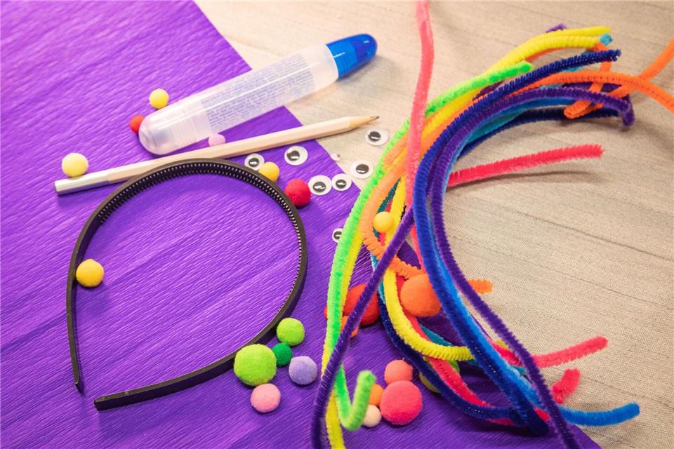 Material für den Jecken-Kopfschmuck: ein Haarreif, bunte Pfeifenreiniger und Bommeln, Kleber und Stift sowie Wackelaugen.Christin Klose/dpa-tmn