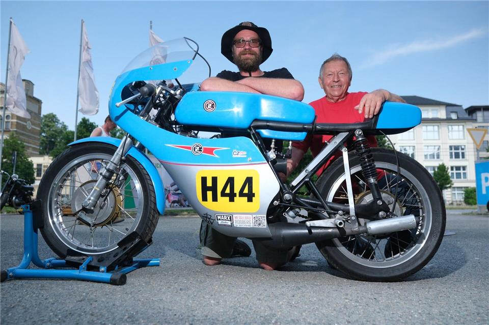 Maximilian Wienhold (l) und Uwe Schneider hocken an einem Rennsport-Motorrad vom Typ CZ 250 aus dem Jahr 1963. Sebastian Willnow/dpa