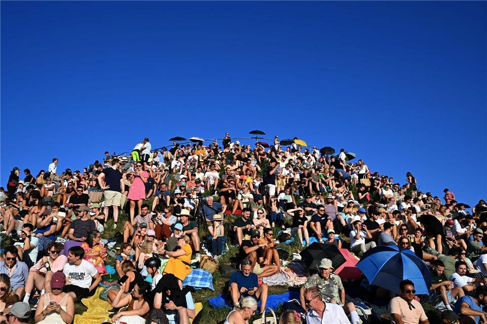 Menschen betrachten eine partielle Sonnenfinsternis am Olympiaberg im Münchner Olympiapark. Felix Hörhager/dpa