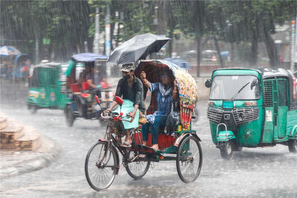 Menschen fahren im Monsunregen durch eine belebte Straße in Dhaka in Bangladesch.Md. Rakibul Hasan Rafiu/ZUMA Press Wire/dpa