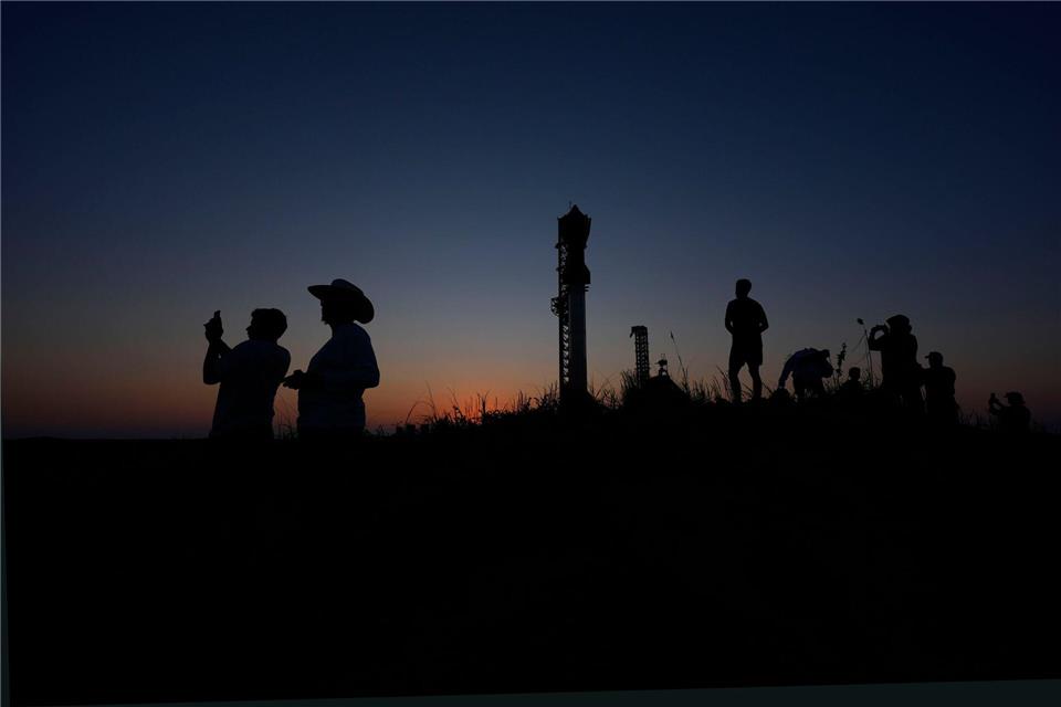 Menschen fotografieren den Sonnenuntergang hinter der Rakete Starship von SpaceX.Eric Gay/AP