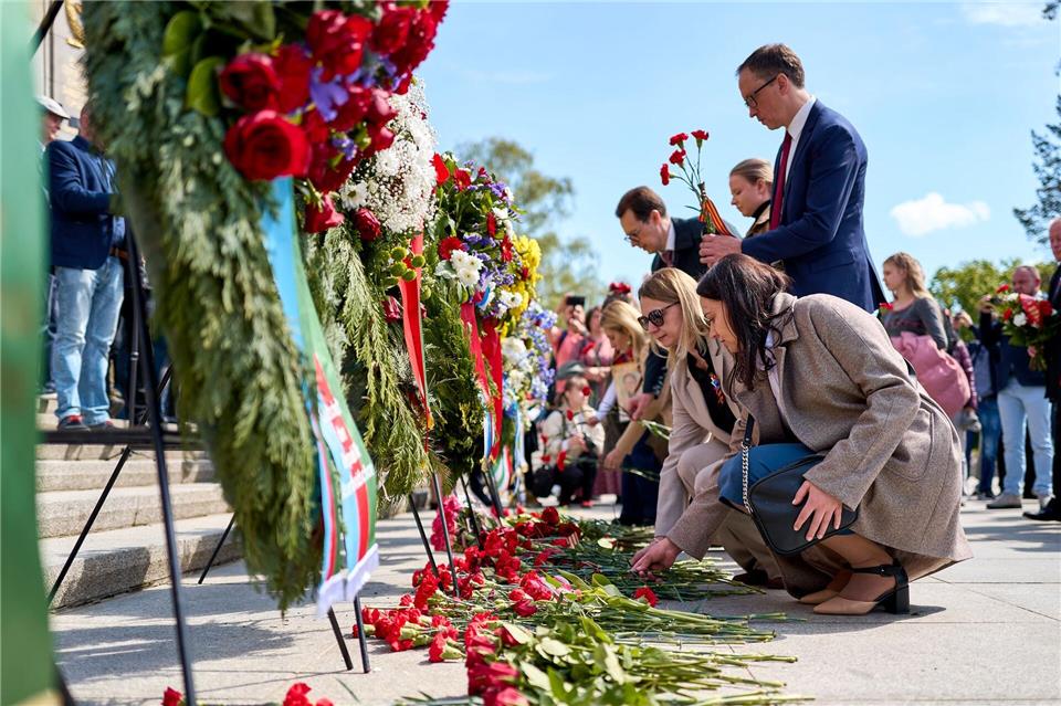 Menschen haben rote Blumen niedergelegt. Michael Ukas/dpa