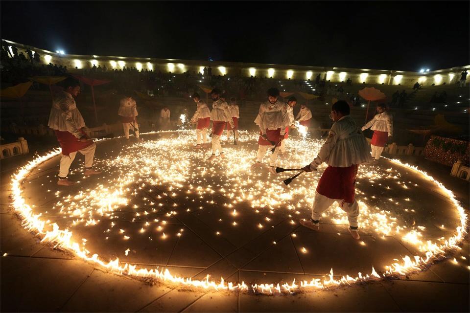 Menschen in traditioneller Tracht führen während der neuntägigen Feierlichkeiten des hinduistischen Festes Navratri in Ahmedabad in Indien den „Mashal Raas“ auf.Ajit Solanki/AP/dpa