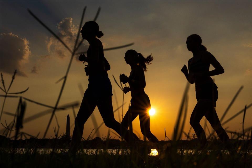 Menschen joggen am Potomac River entlang, während die Sonne in der Nähe des Washington Monument aufgeht.Tom Brenner/AP/dpa