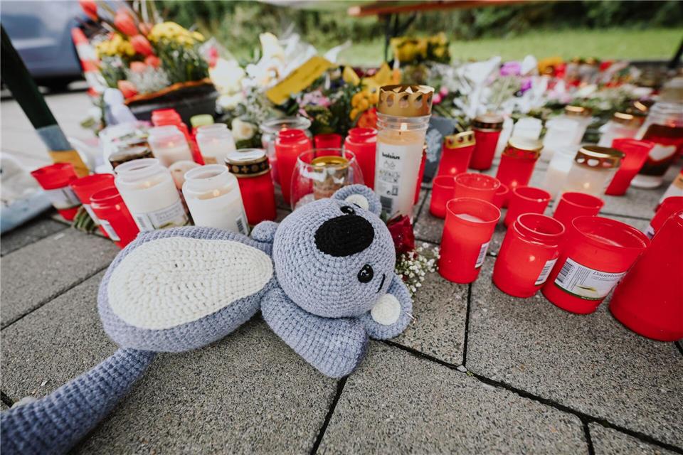 Menschen legen Blumen und Kerzen auf dem abgesperrten Parkplatz in Niedernhall nieder.Marius Bulling/dpa