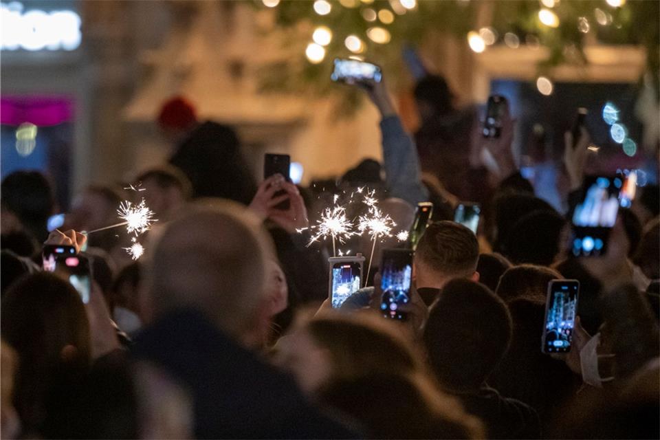 Menschen machen Fotos mit ihren Smartphones, während sie den Jahreswechsel feiern.