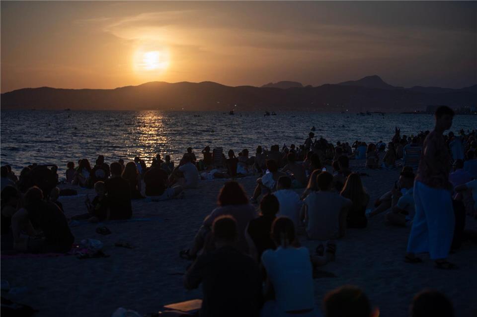 Menschen sitzen am Strand von Palma und warten auf die totale Sonnenfinsternis.Clara Margais/dpa