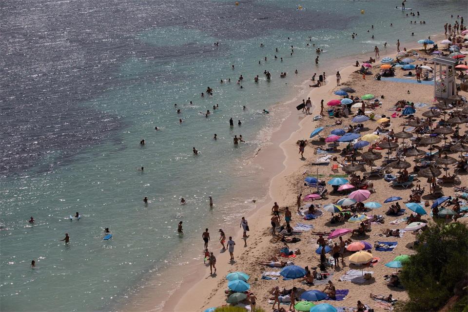Menschen sonnen sich und entspannen am Meer am Strand von Caleta de Portals Nous auf Mallorca.Clara Margais/dpa