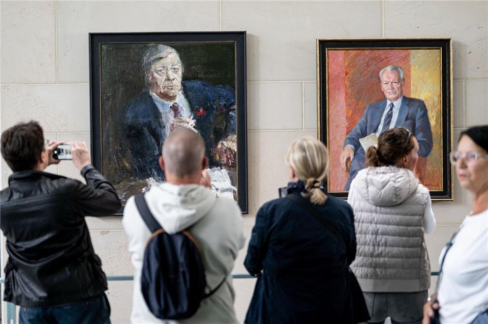 Menschen stehen am Tag der offenen Tür der neuen Bundesregierung im Kanzleramt vor den Porträts der ehemaligen Kanzlern Schmidt (l) und Brandt.Fabian Sommer/dpa