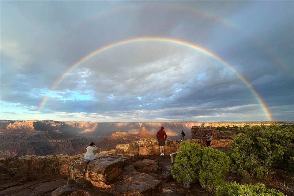 Bilder des Tages Menschen stehen an einem Aussichtspunkt, während ein doppelter Regenbogen am Himmel über dem Dead Horse Point State Park in der Nähe von Moab in den USA leuchtet.Becky Bohrer/AP/dpa