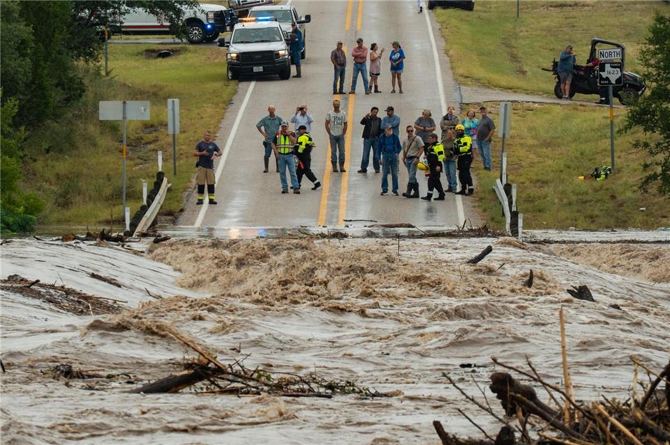 Menschen stehen zusammen und beobachten, wie der Perdenales River die Ranch Road 1623 in  in Texas überflutet.Mikala Compton/Austin American-Statesman/AP/dpa