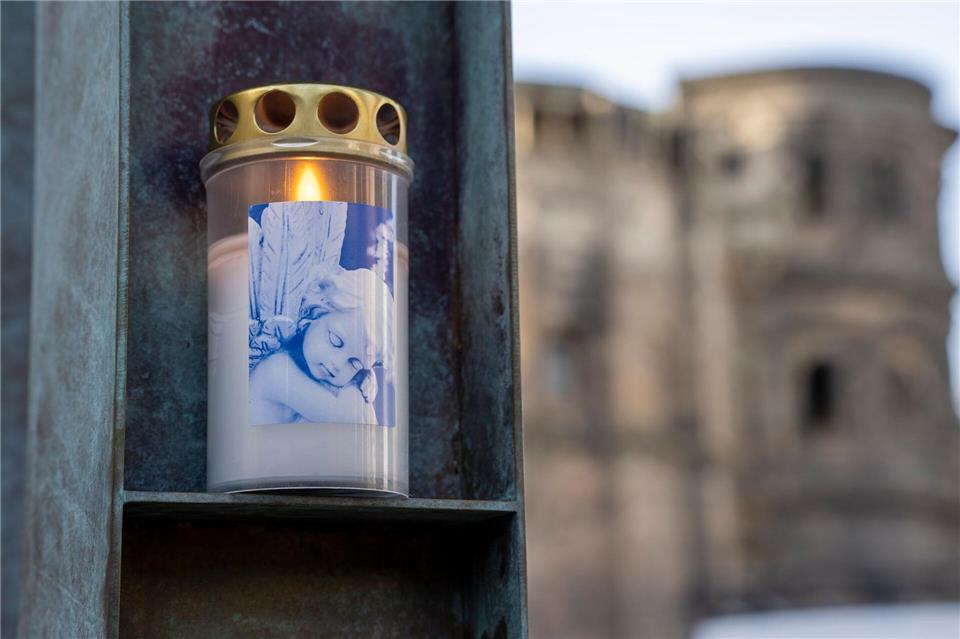 Menschen stellen Kerzen auf und legen Blumen nieder.Harald Tittel/dpa