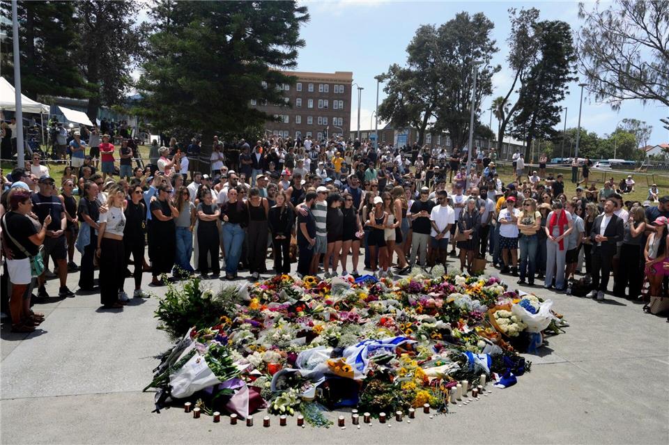 Menschen versammelt sich einen Tag nach einer Schießerei am Bondi Beach in Sydney um ein Blumendenkmal.Mark Baker/AP/dpa