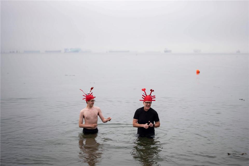 Menschen waten im Wasser während des olar Bear Swim in Vancouver.ETHAN CAIRNS/The Canadian Press/AP/dpa