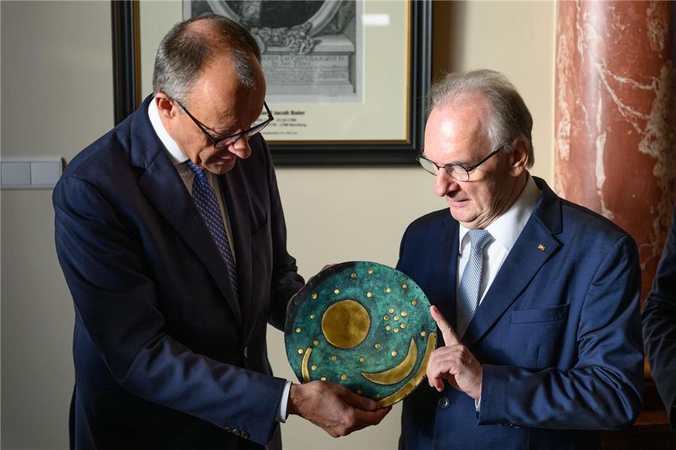 Merz nimmt eine Nachbildung der Himmelsscheibe von Nebra entgegen.Robert Michael/dpa