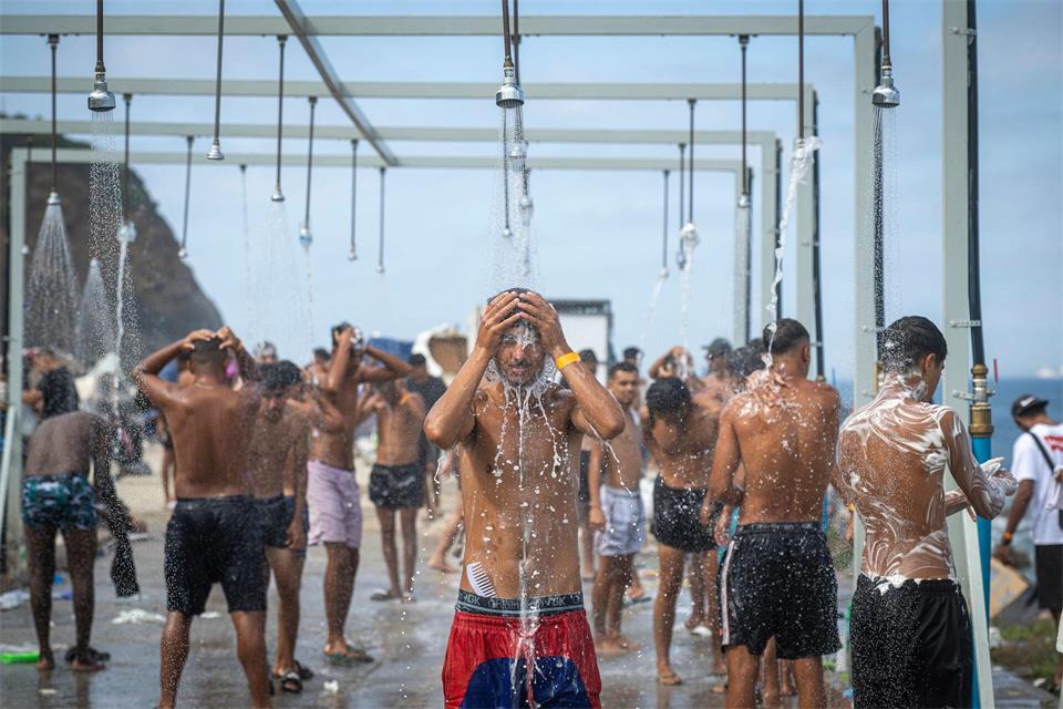 Migranten duschen in einer Anlage am Strand von El Trampolín in der spanischen Exklave Ceuta, wo zahlreiche provisorische Unterkünfte errichtet wurden.Marcos Moreno/EUROPA PRESS/dpa