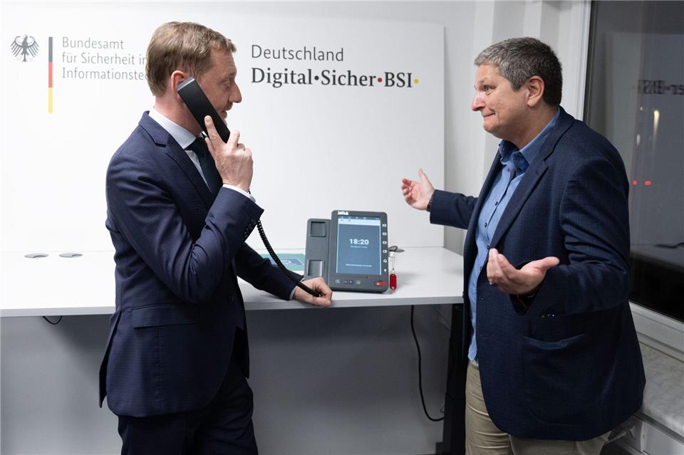Ministerpräsident Michael Kretschmer (l) informierte sich über eine hochsichere Telefonie-Lösung. Sebastian Kahnert/dpa