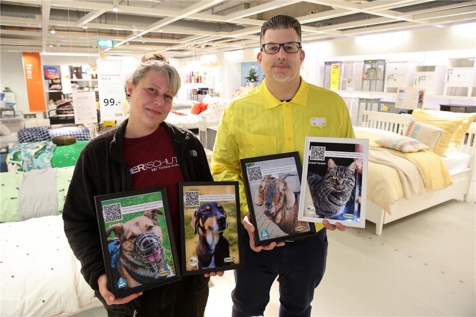 Mit Fotos werben Tierheimleiterin Sarah Ross und Ikea-Abteilingsleiter Gerrit Kaminski mitten in der Möbelausstellung für schwer vermittelbar Tiere.Christian Butt/dpa