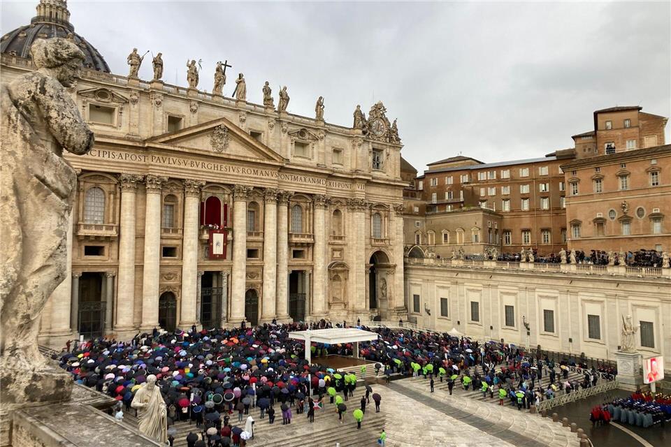 Mit Regencapes und unter Regenschirmen verfolgten die Gläubingen die Ansprache des Papstes.Sabine Dobel/dpa