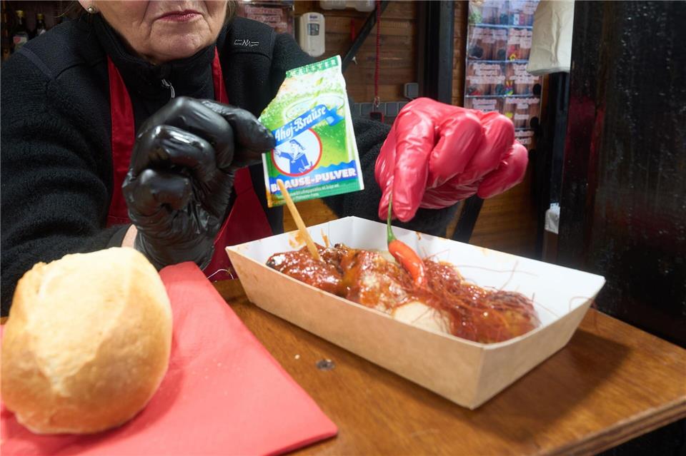 Mit dem gewissen Prickeln: Ingrid Meyer dekoriert beim Festival der Currywurst eine Currywurst im Ahoi-Brause-Stil. Thomas Frey/dpa/dpa-tmn