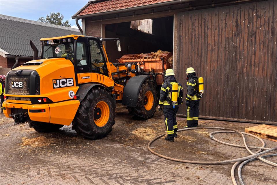 Mit einem Bagger holt die Feuerwehr das Stroh aus der Scheune, um dann unter Atemschutz die Löscharbeiten zu leisten.