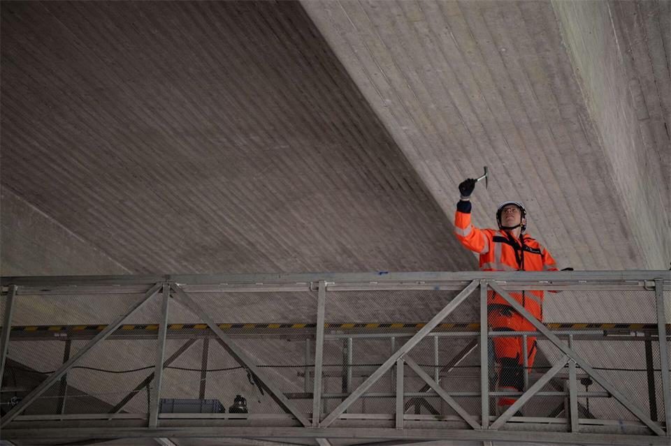Mit einem Hammer klopfen Prüfer die Brücke von unten ab, um Schäden festzustellen.Katharina Kausche/dpa