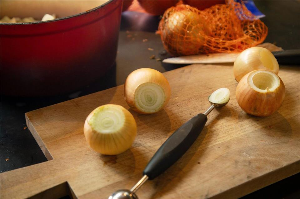 Mit einem Parisienne-Löffel oder einem Kugelausstecher wird die ungeschälte Zwiebel ausgehöhlt.Christin Klose/dpa-tmn