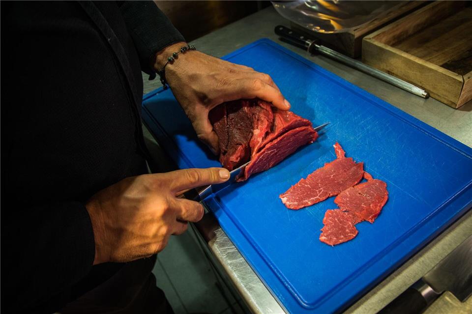 Mit einem scharfen Messer schneidet René Tepper dünne gleichmäßige Scheiben vom Rinderfilet ab. Christin Klose/dpa-tmn