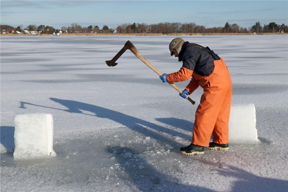 Mit einer Hacke öffnet Andy Ahrens ein altes Eisloch auf dem Bodden.Bernd Wüstneck/dpa