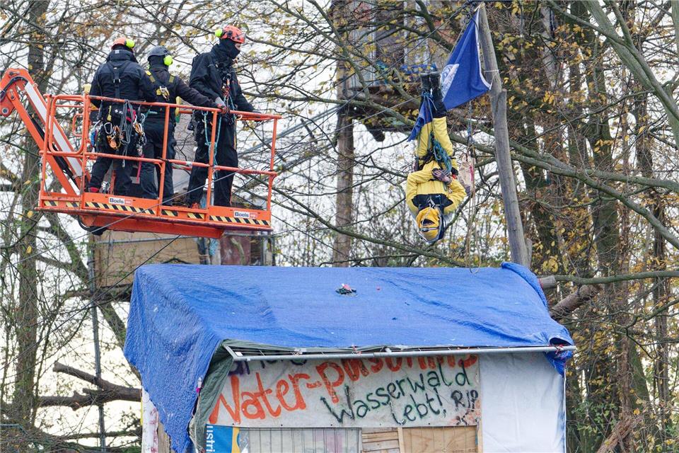 Mit einer Hebebühne nähern sich Polizisten einem Aktivisten, der kopfüber in einem Baum hängt. (Archivbild)Henning Kaiser/dpa