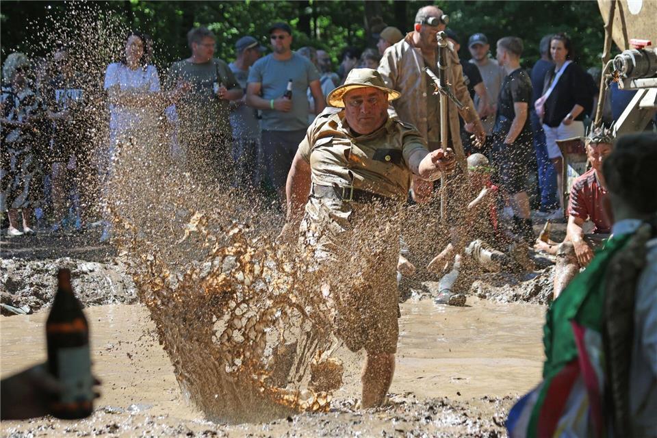 Mit lautem Peitschenknallen werden die „Dreckschweine“ aus einem mit Schlamm gefüllten Loch getrieben.Matthias Bein/dpa