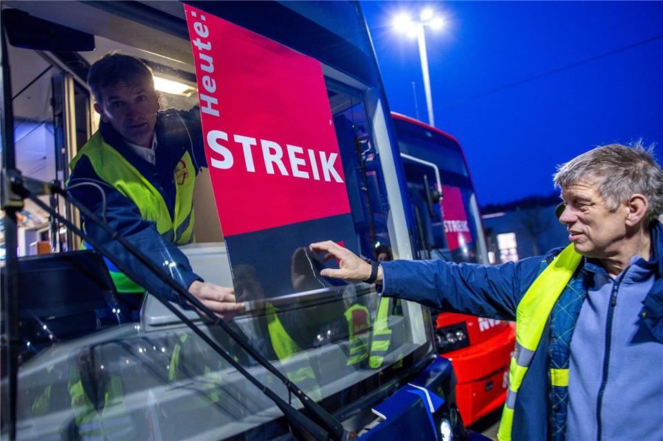 Mitarbeiter befestigen auf dem Betriebshof in Schwerin ein Streik-Plakat an der Frontscheibe einer Straßenbahn.Jens Büttner/dpa