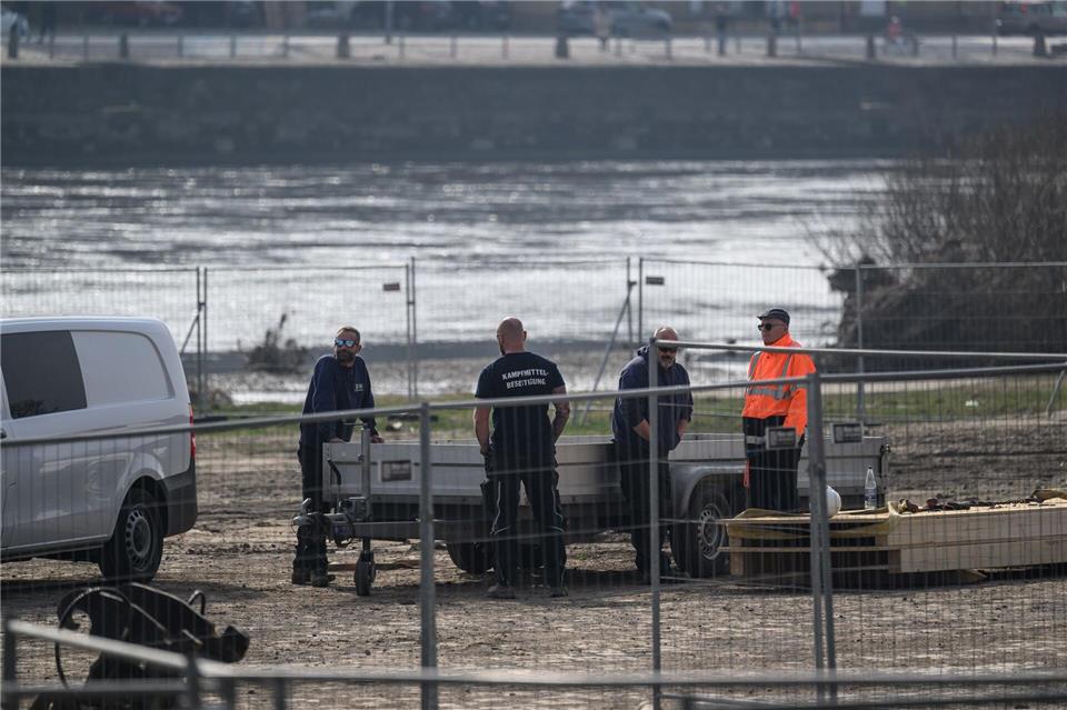 Mitarbeiter der Kampfmittelbeseitigung stehen auf der Baustelle an der abgerissenen Carolabrücke am Elbufer.Robert Michael/dpa