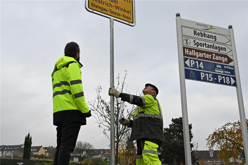 Mitarbeiter des Baubetriebshofes stellen ein neues Ortsschild auf.Michael Brandt/dpa