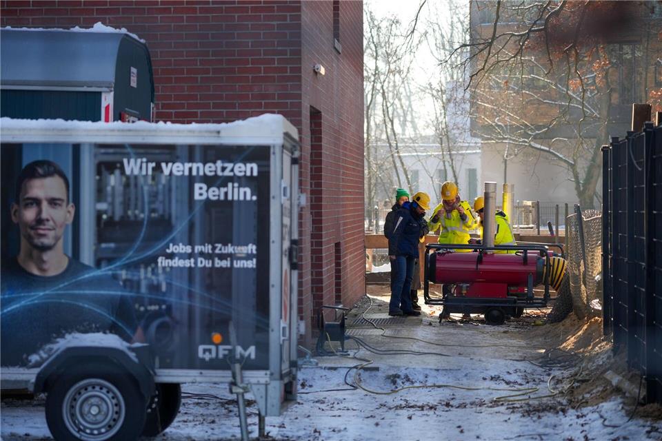 Mitarbeiter des Umspannwerkes an der Argentinischen Allee stehen hinter einem Zaun nebeneinander.Soeren Stache/dpa