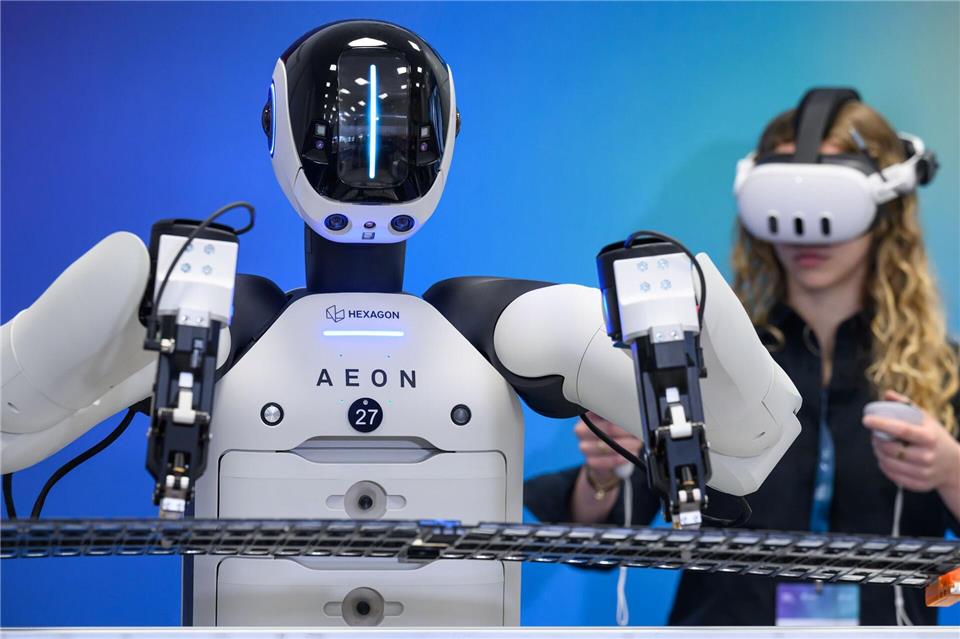 Mitarbeiter trainieren einen humanoiden Roboter für den Umgang mit Bauteilen von Elektroauto-Batterien.Hendrik Schmidt/dpa