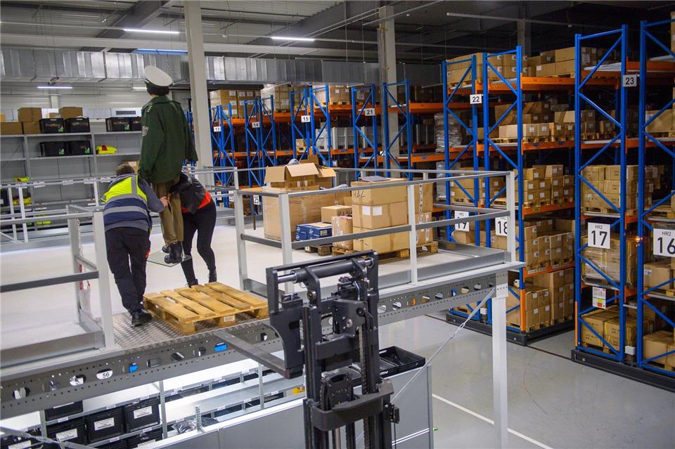 Mitarbeiter vom Bekleidungsservicecenter der Polizeiinspektion Zentrale Dienste bereiten im Lager eine Pressekonferenz vor und heben eine Puppe mit noch grüner Dienstuniform von einem Gabelstapler herunter.Klaus-Dietmar Gabbert/dpa