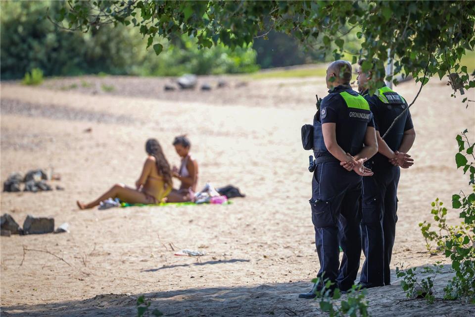 Mitarbeiter vom Ordnungsamt der Stadt Düsseldorf sind am sogenannten Paradiesstrand im Einsatz. Sie überwachen das Badeverbot im Rhein. Christoph Reichwein/dpa