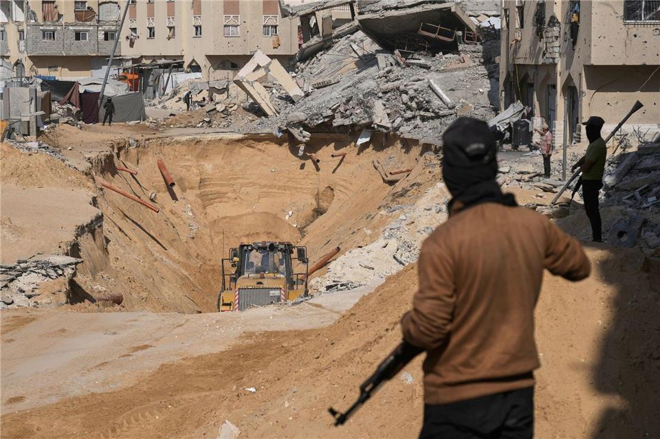 Bilder des Tages Mitglieder der militanten Hamas-Gruppe graben nach den Leichen israelischer Geiseln inmitten zerstörter Gebäude im südlichen Gazastreifen.Abdel Kareem Hana/AP/dpa