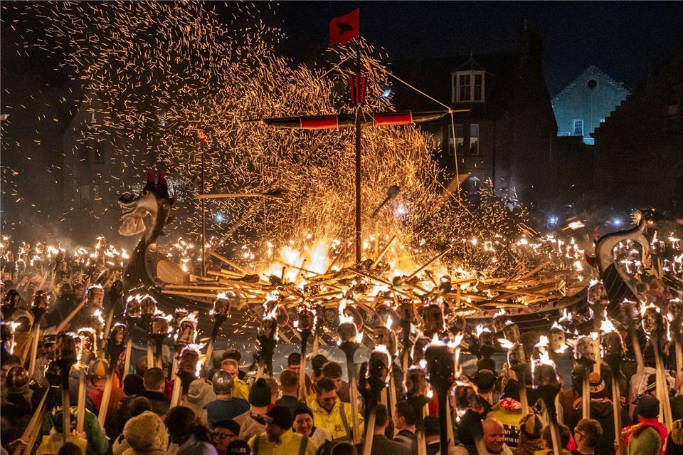 Mitglieder vom Jarl Squad zünden eine Galeere in Lerwick auf den Shetlandinseln während des Up Helly Aa-Festivals an. Jane Barlow/PA Wire/dpa