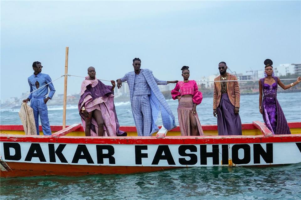 Models präsentieren Kreationen auf einem traditionellen Fischerboot.Misper Apawu/AP/dpa