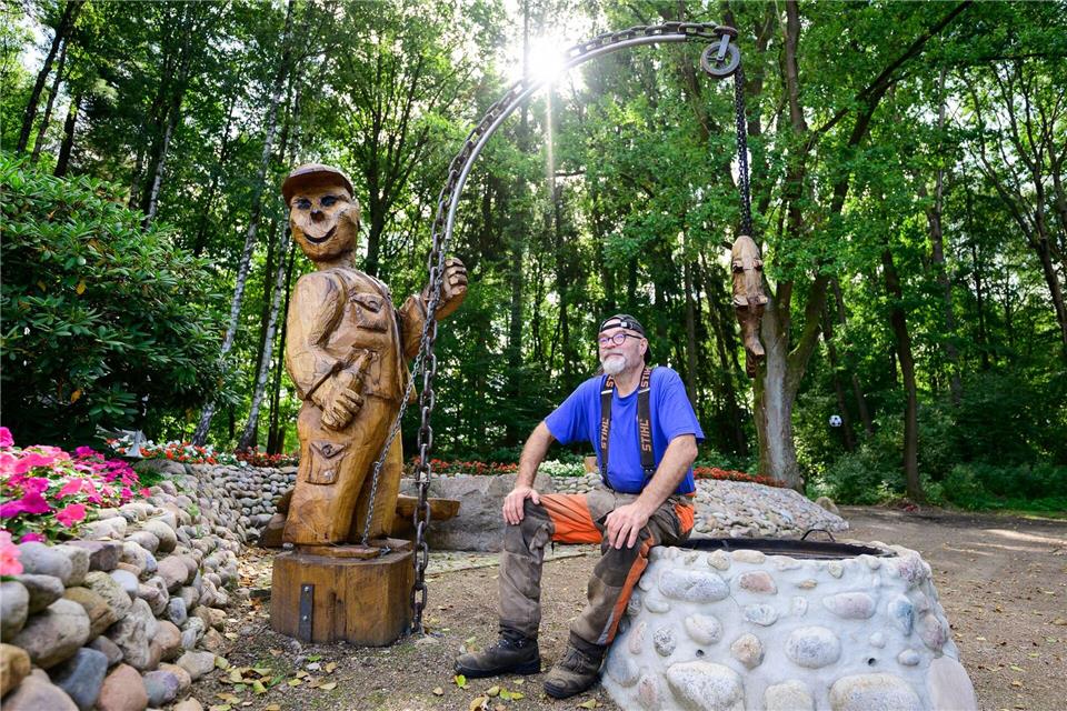 Motorsägenkünstler Andree Löbnitz neben einer Holzskulptur, die er aus einem Holzstamm schnitzte.Philipp Schulze/dpa