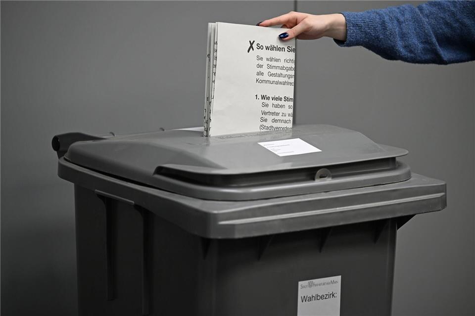 Mülltonnen-Look bei Kommunalwahlen - eine Frau wirft einen Stimmzettel in eine Wahlurne. (Archivbild)Michael Brandt/dpa