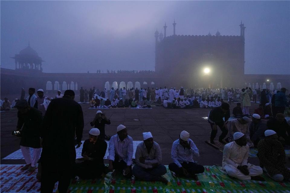 Muslime warten im Morgennebel in der Jama Masjid in Neu Delhi auf das Eid al-Fitr-Gebet am Ende des heiligen Fastenmonats Ramadan.Manish Swarup/AP/dpa