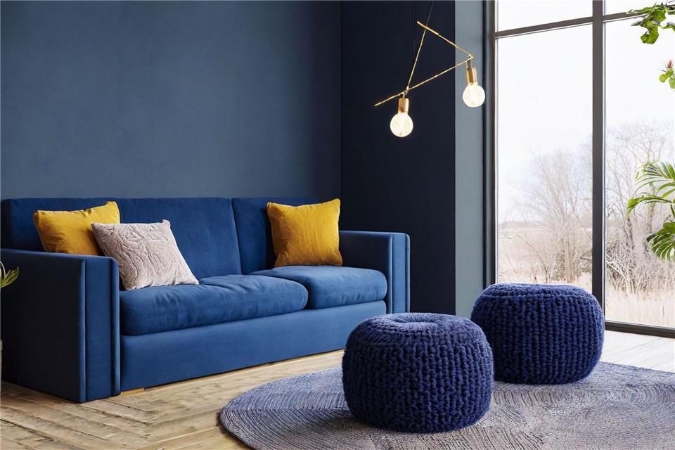 Mut zur Farbe: Dunkelblaue Wände und ein passendes Sofa schaffen eine gemütliche Atmosphäre und laden zum Entspannen ein.Erismann/DTI/dpa-tmn