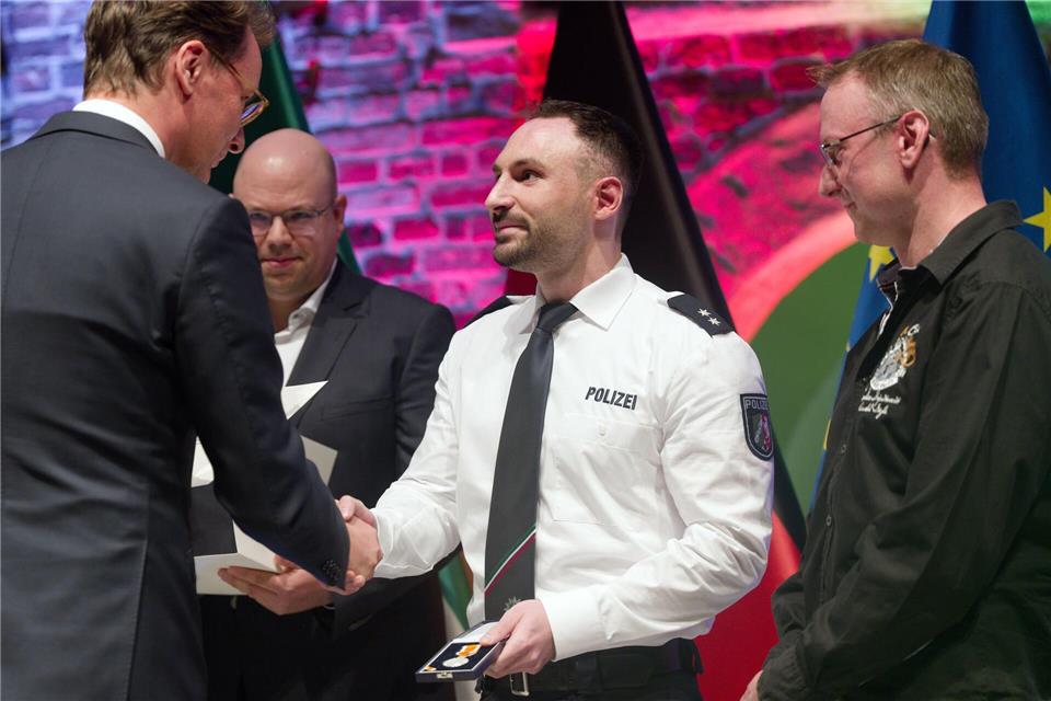 NRW-Ministerpräsident Hendrik Wüst (CDU) hat Einsatzkräfte, die im Mai 2023 Opfer eines Mordanschlags in einem Ratinger Hochhaus wurden, mit der Rettungsmedaille des Landes ausgezeichnet. Darunter ist der 32-jährige Polizeioberkommissar Enver G. (Mitte).Henning Kaiser/dpa